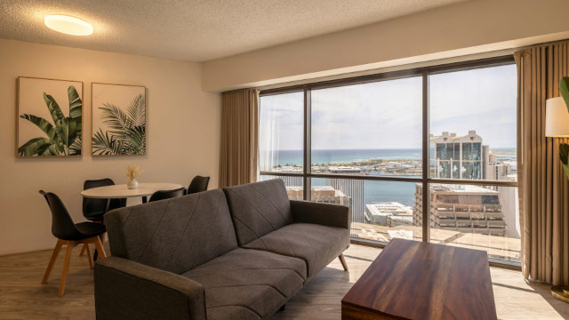 Living room area with sofa coffee table and dining room with view of Honolulu Harbor